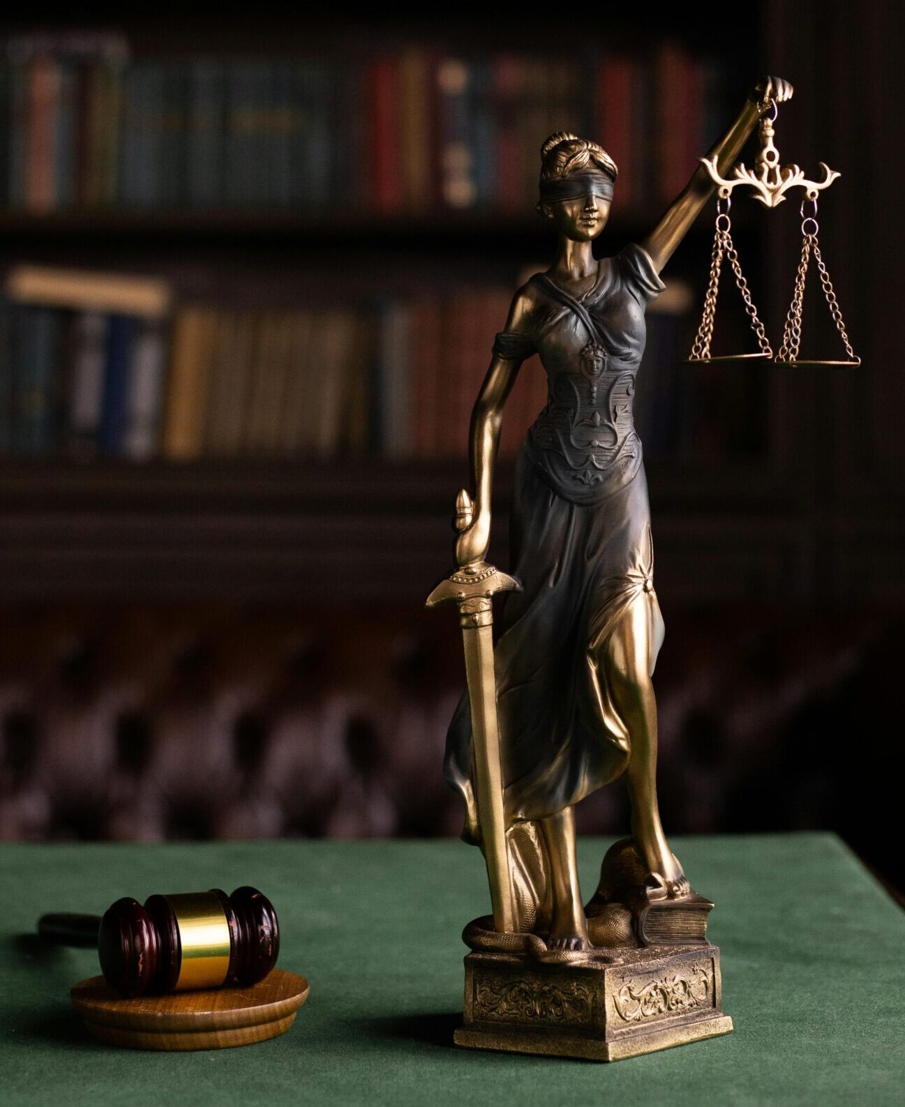 Lady Justice and gavel on a table in a classic law library setting.